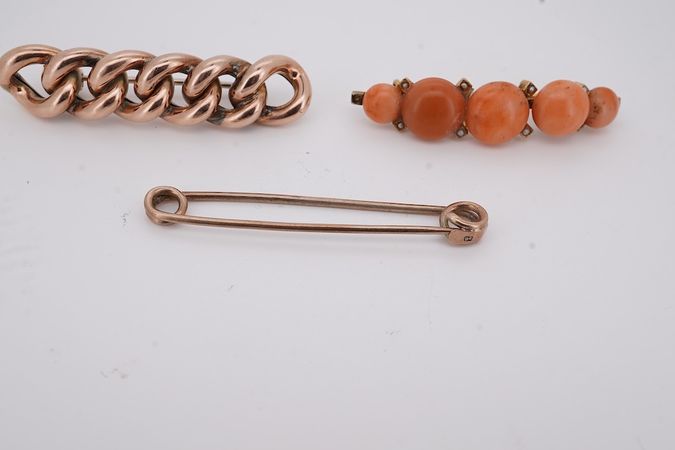 An early 20th century yellow metal and graduated five stone coral bead brooch, with seed pearl spacers, 45mm, together with a yellow metal curb link brooch and a yellow metal (stamped 9c) safety pin. Condition - fair